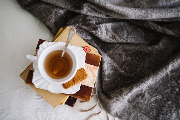 Free photo tea on pile of books near blanket