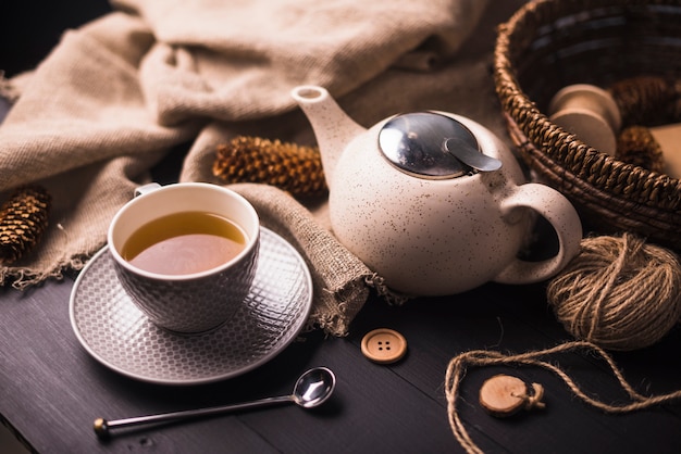 Tea; pinecone; teapot; button; sack and wicker basket on table