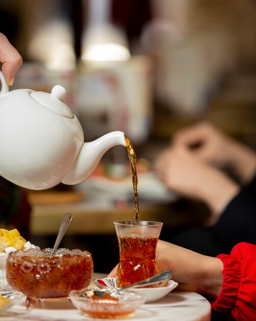 Tea poured into armudu glass from teapot served with jam