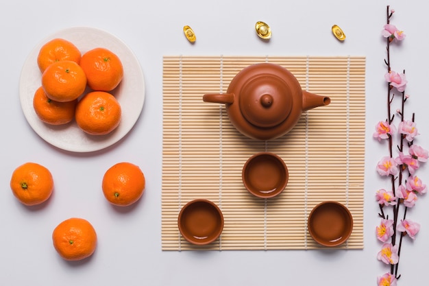 Бесплатное фото Чайный набор между мандаринами и веткой сакуры