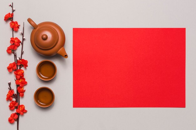 Tea set and branch near red paper