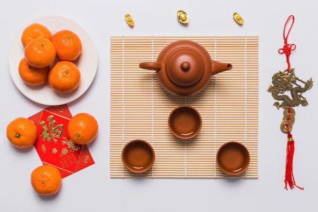 Tea set near tangerines and Chinese decoration
