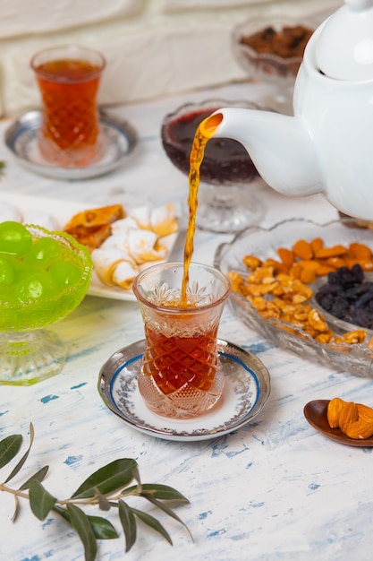 Tea set with varieties of traditional nuts, lemon, confiture and sweets served on white tablecloth 