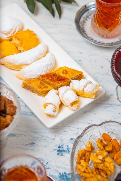 Tea set with varieties of traditional nuts, lemon, confiture and sweets served on white tablecloth 