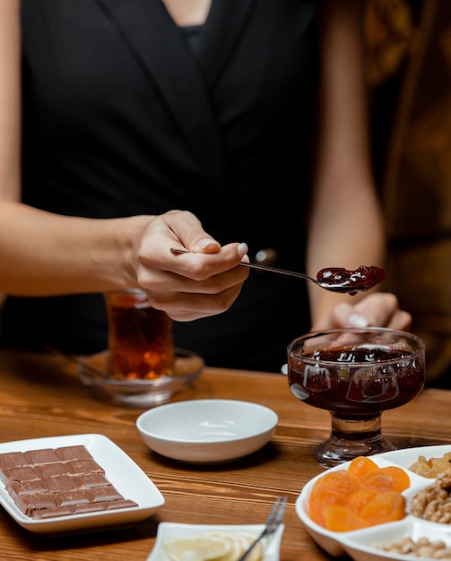 Foto gratuita preparazione del tè con marmellata di fragole, tè nero, barretta di cioccolato, frutta secca