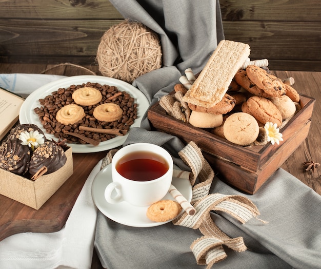 Tea table with pralines, cookies and a cup of tea