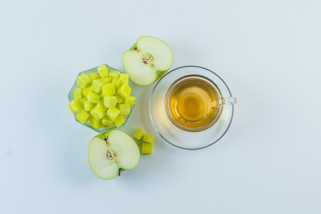 Tea with apple, sugar cubes in a mug on white background, flat lay.