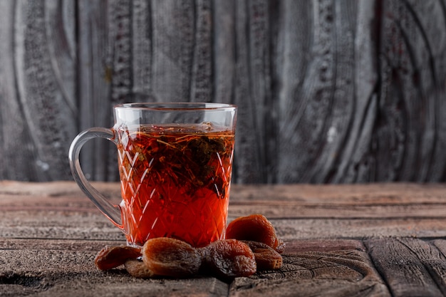 Free photo tea with dried fruits in a cup on stone tile and wooden surface