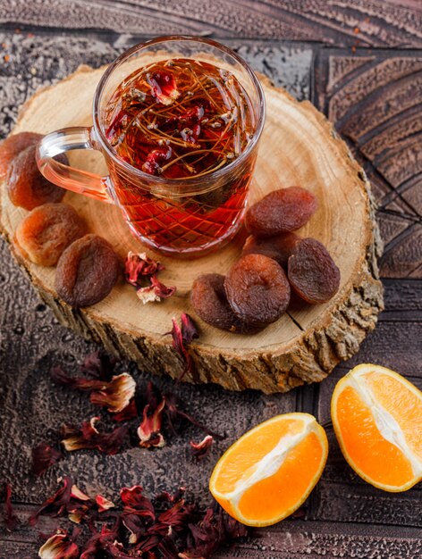 Tea with dried fruits, herbs, orange, wood in a cup on stone tile surface