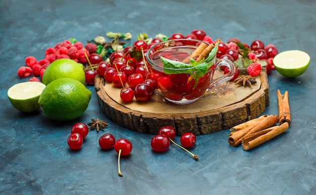 Tea with herbs, fruits, spices in a mug on wooden board and stucco background, high angle view.