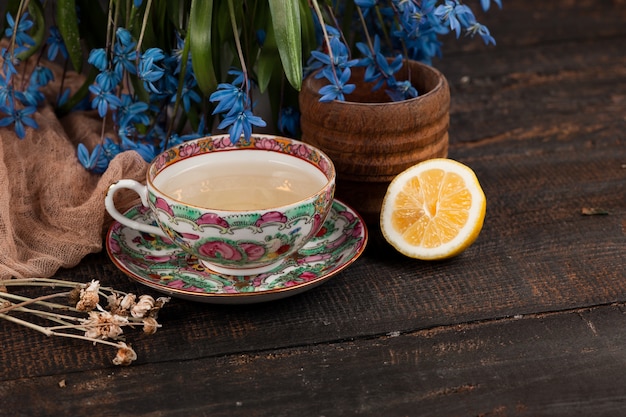 レモンとテーブルの上の青いサクラソウの花束とお茶