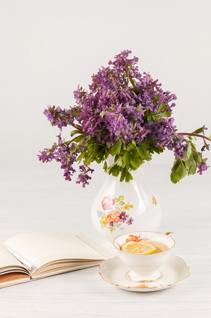 Tea with  lemon and bouquet of  lilac primroses on the table