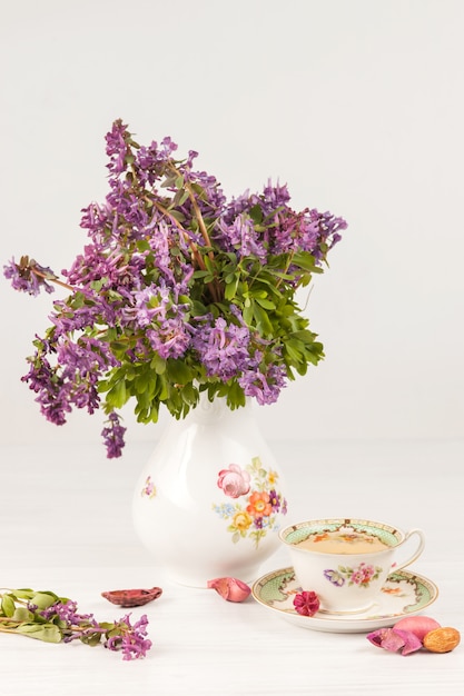 Free photo tea with  lemon and bouquet of  lilac primroses on the table