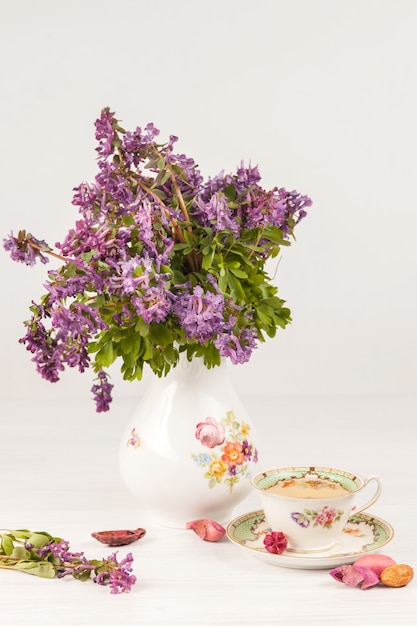 Tea with  lemon and bouquet of  lilac primroses on the table