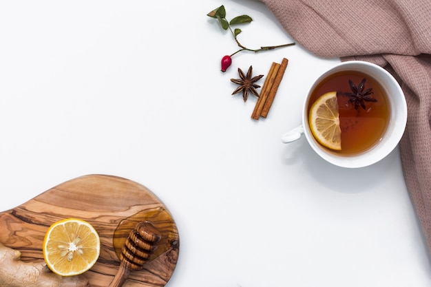Чай с лимоном возле доски с медовым ковшом