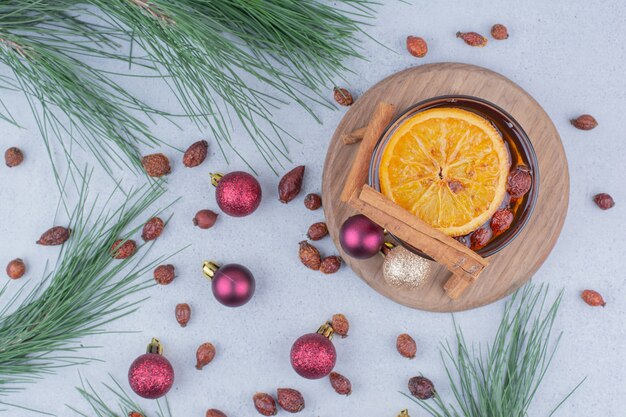 Tea with rosehips and Christmas balls on marble surface. 