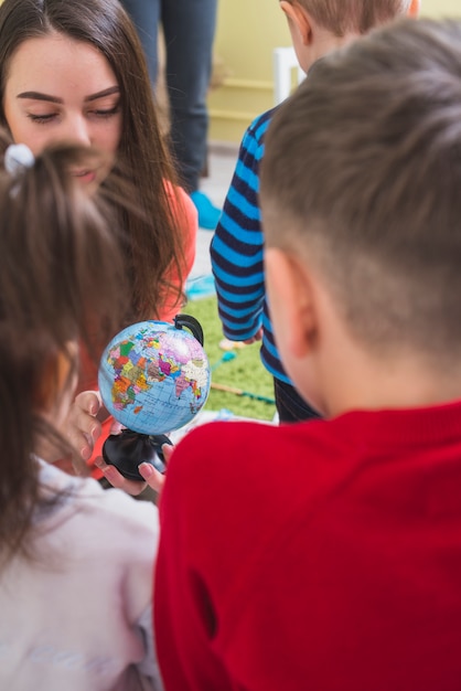 Insegnante e bambini che guardano globo