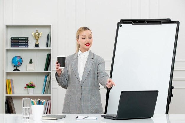 Teacher cute instructor in suit in classrom with computer and whiteboard holding coffee cup