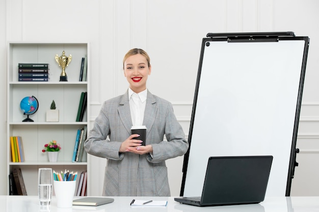 Teacher cute instructor in suit in classrom with computer and whiteboard holding paper cup