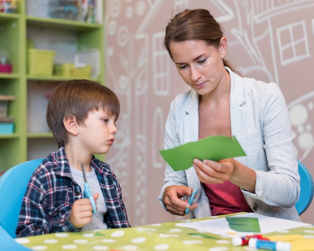 Teacher cutting paper for boy