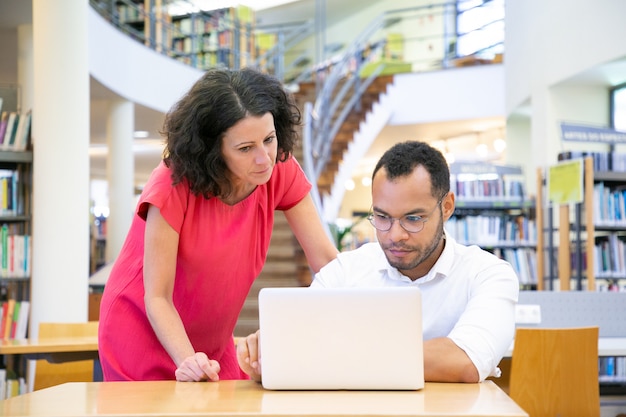 Teacher giving help to student working on project