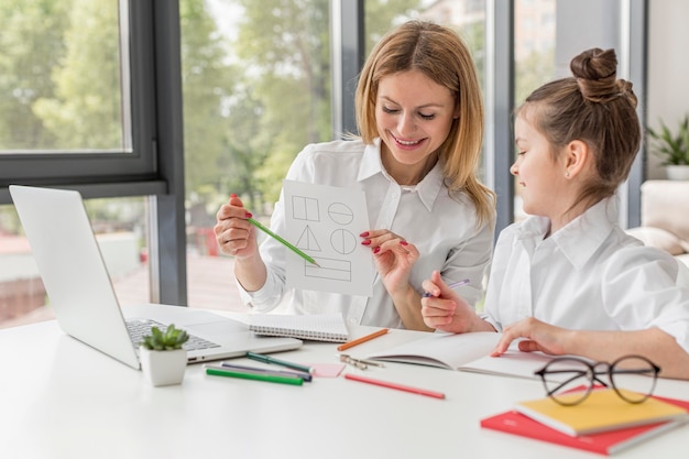 Free photo teacher helping her daughter study indoors