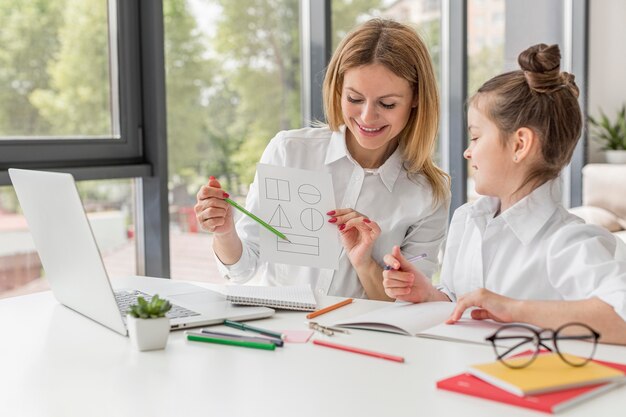 Teacher helping her daughter study indoors