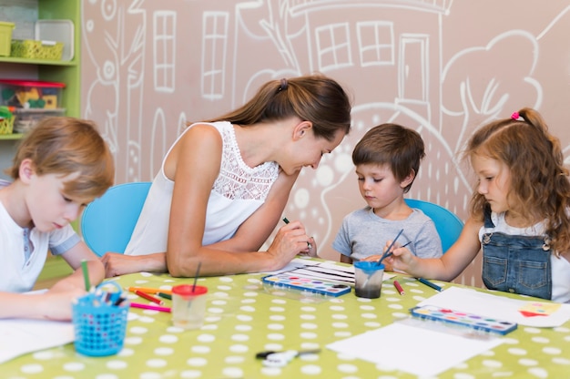 Free photo teacher helping kid paint