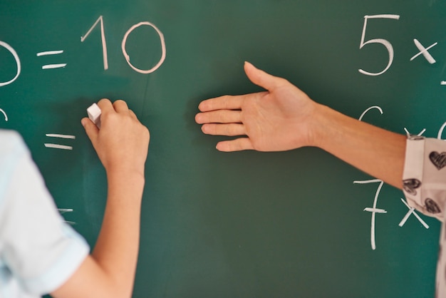 Free photo teacher and her pupil next to the blackboard