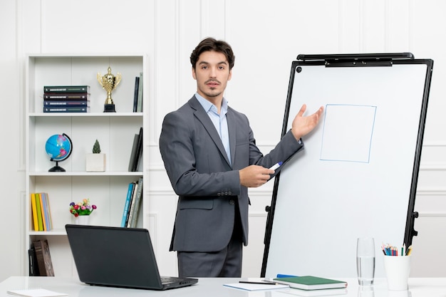 Free photo teacher smart instructor in grey suit in classroom with computer whiteboard explaining geometry