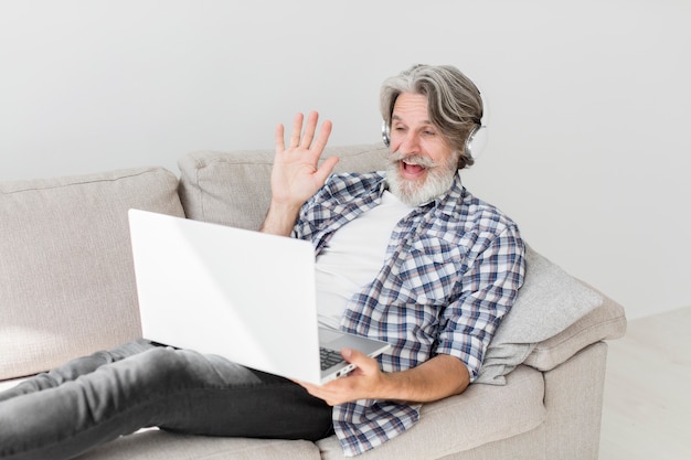 Teacher staying on couch waving at laptop