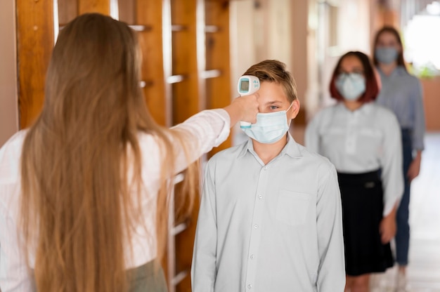 Teacher taking body temperature at school