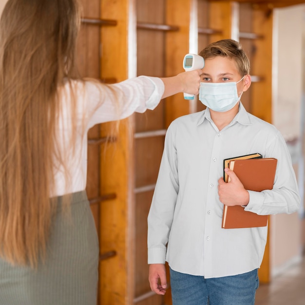 Teacher taking body temperature at school