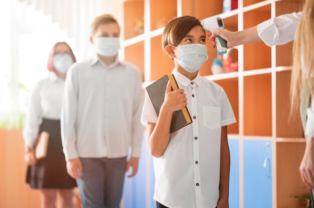 Teacher taking body temperature at school