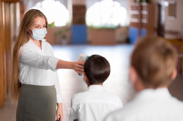 Teacher taking body temperature at school