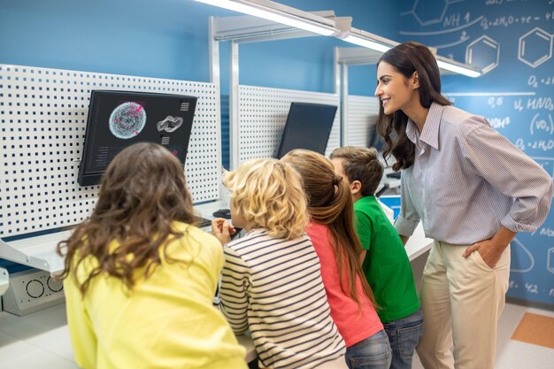 Учитель с детьми смотрит на экран на уроке
