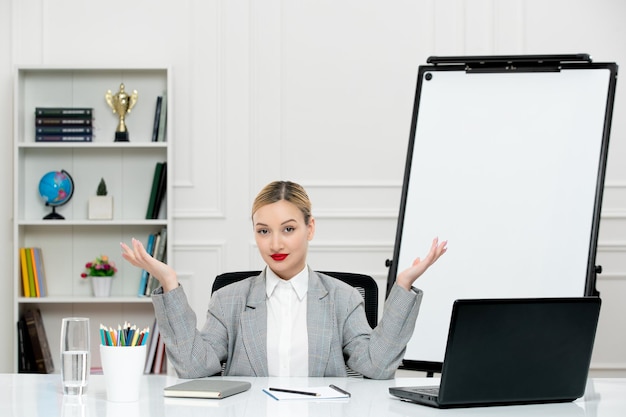 Free photo teacher young cute instructor in grey suit in classrom with laptop and whiteboard waving hands