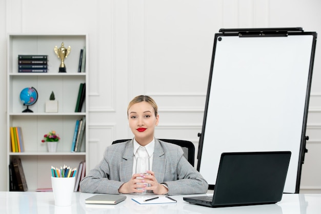 Free photo teacher young cute instructor in suit in classrom with laptop and whiteboard crossing hands