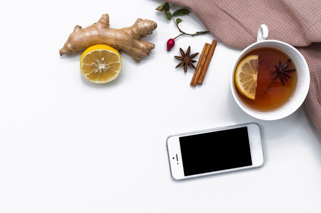 Teacup with lemon and ginger near smartphone