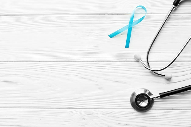 Free photo teal ribbon near stethoscope on lumber background