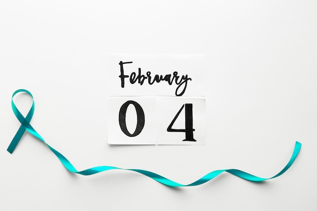 Free photo teal ribbon below world cancer day date