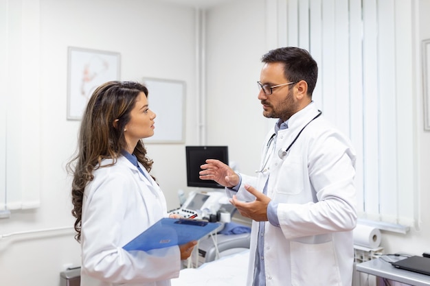 Team of doctors working together on patients file at hospital Medical staff analyzing report and working at clinic Woman doctor having discussion in a hospital with colleague