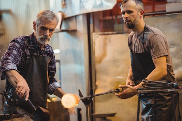 Team of glassblower forming and shaping a molten glass