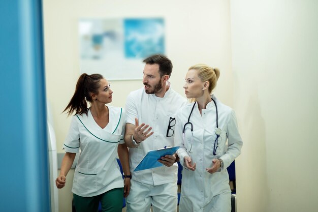 Team of healthcare workers talking about medical reports while rushing through the lobby in the hospital