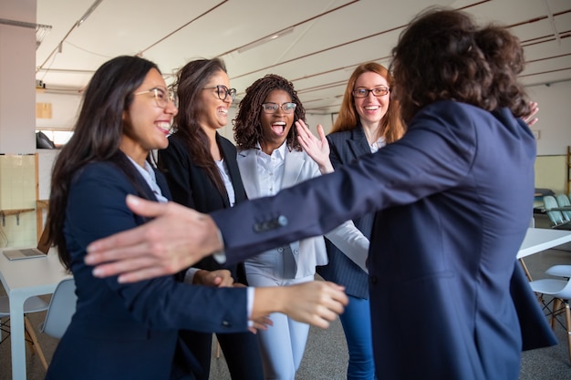 Free photo team leader hugging her happy younger colleagues