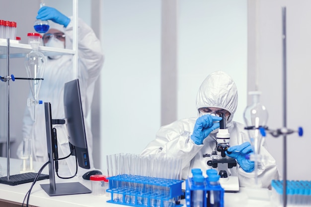 Team of medical scientist in modern laboratory searching for coronavirus vaccine wearing ppe. Chemist researcher during global pandemic with covid-19 checking sample in biochemistry lab