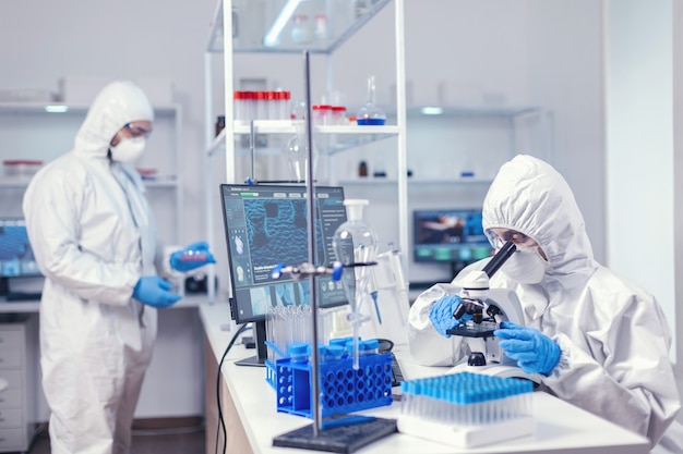 Free photo team of medical scientist wearing ppe suit against coronavirus working to find a cure. chemist researcher during global pandemic with covid-19 checking sample in biochemistry lab