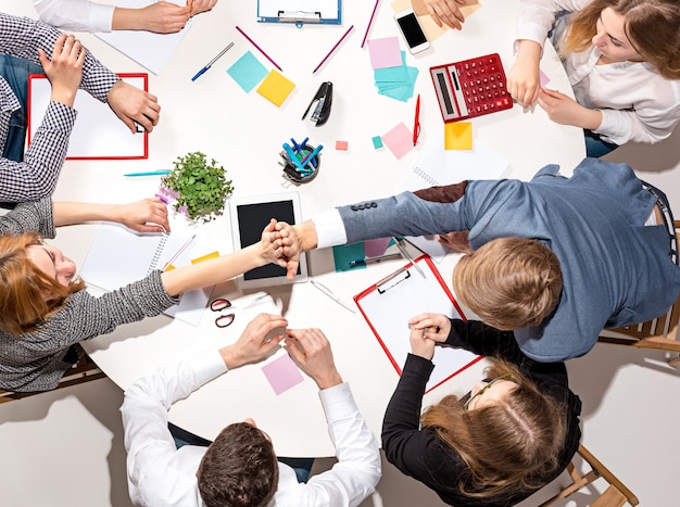 Team sitting behind desk, checking reports, talking. Top View. The business concept of collaboration, team work, meeting