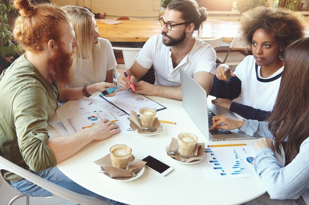 Team of young colleagues having meeting at cafe