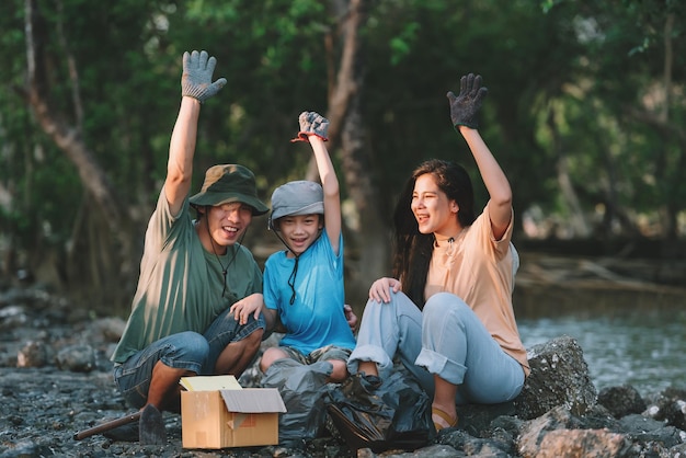 Teamwork of asian family environment conservation volunteer help to picking plastic and foam garbage on mangrove forest areaVolunteering save world concept